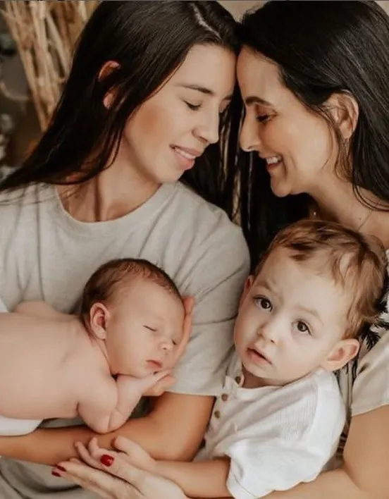 Two mothers holding their newborn and toddler