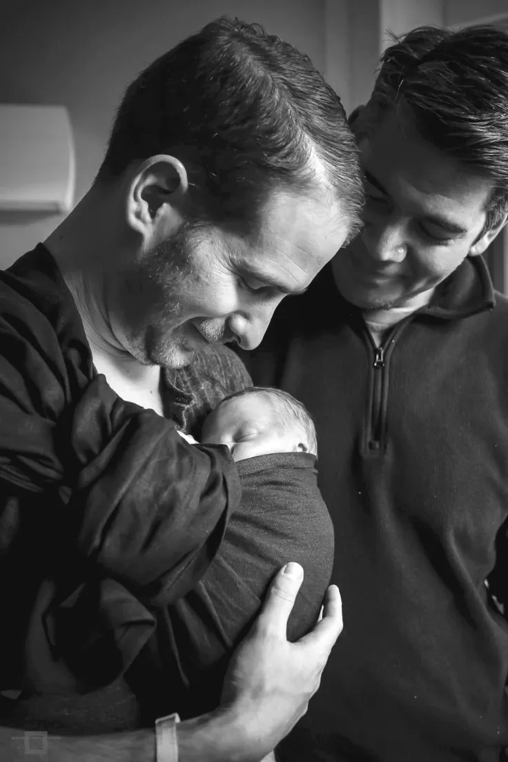 Two fathers holding their newborn