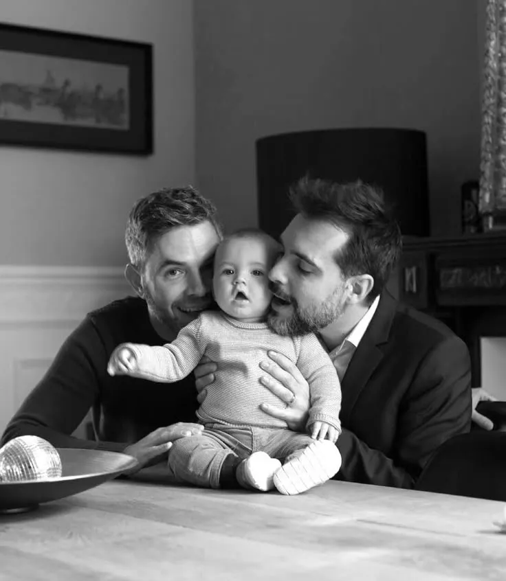 Two fathers with their baby at home