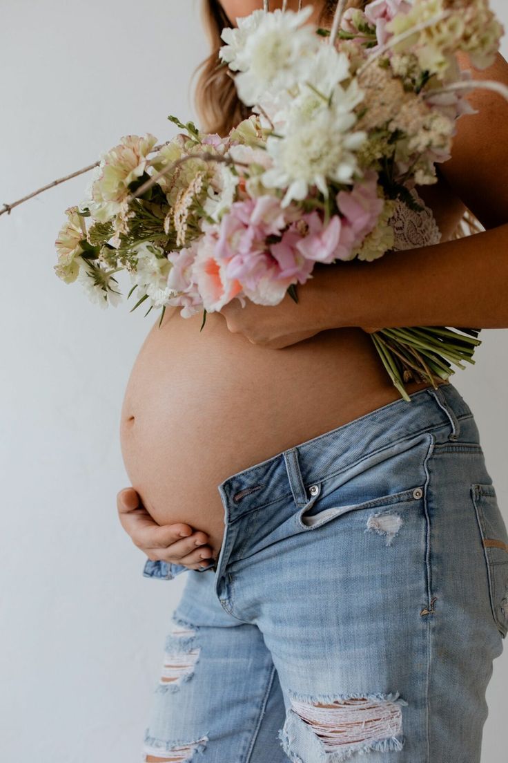 A pregnant surrogate holding a bouquet of flowers
