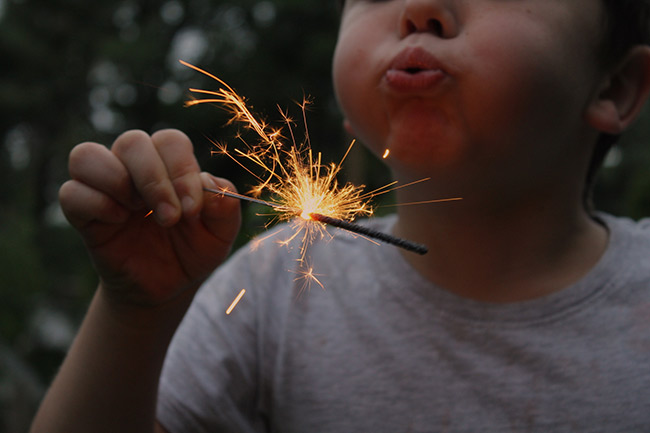 Surrogate toddler blowing on sparkler
